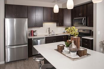 Kitchen with espresso cabinetry, granite countertops, and stainless steel appliances.